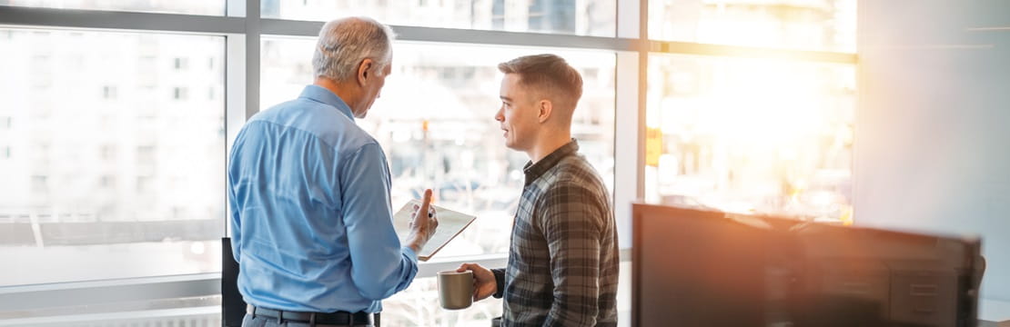Two male coworkers talking in an office.